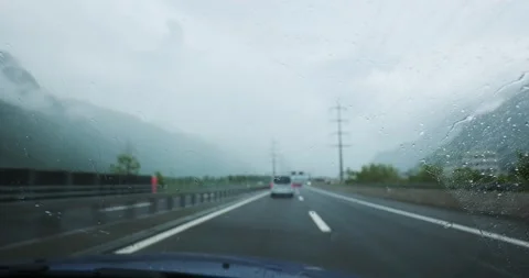Car driving on a highway in heavy rain with windshield wipers moving Stock Footage 336049099