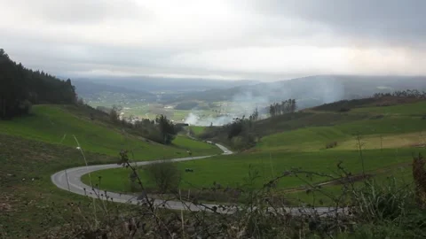 Car driving up mountain road overlooking Lourenza valley with bonfire Stockbeeldmateriaal 332445140