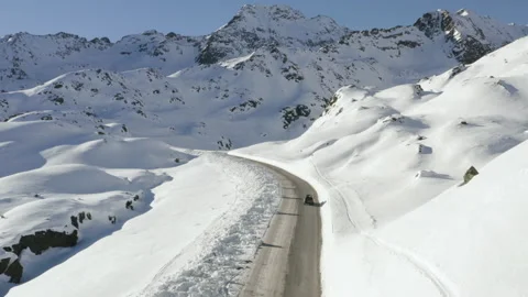 Car driving on mountain road surrounded by snowy Austrian Alps. 4k drone view. Stock Footage 143321940