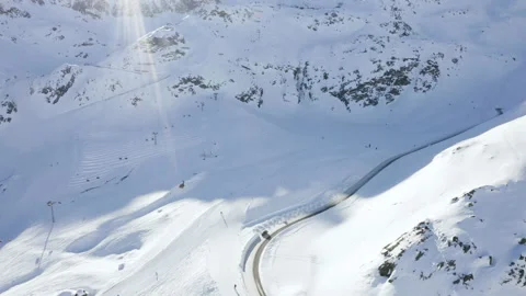 Car driving on mountain road surrounded by snowy Austrian Alps. 4k drone view. Stock Footage 143322128