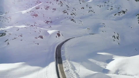 Car driving on mountain road surrounded by snowy Austrian Alps. 4k drone view. Stock Footage 143322243