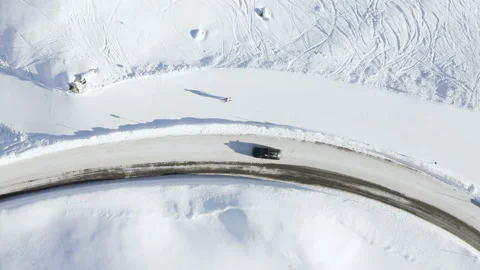Car driving on mountain road surrounded by snowy Austrian Alps. 4k drone view. Stock Footage 143322394