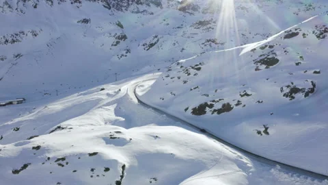 Car driving on mountain road surrounded by snowy Austrian Alps. 4k drone view. Stock Footage 143322500