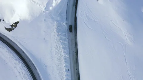 Car driving on mountain road surrounded by snowy Austrian Alps. 4k drone view. Stock Footage 143325913
