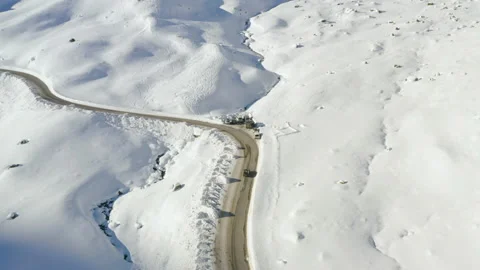 Car driving on mountain road surrounded by snowy Austrian Alps. 4k drone view. Stock Footage 143327859