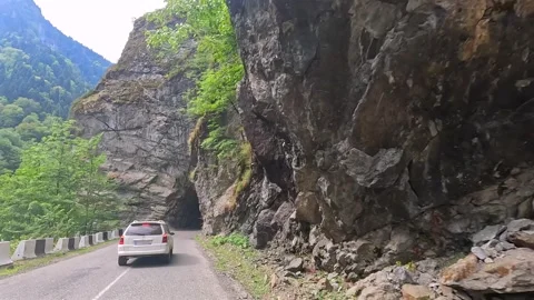 Car driving in rear view through a narrow rock tunnel on a mountain road Stock Footage 343776114