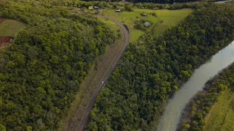 Car driving on a road between green fields, forests and a river. Stock Footage 317657350