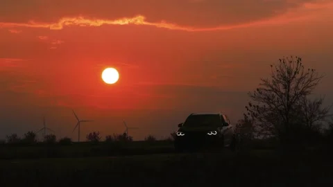 Car driving on road at sunset with wind turbines Video stock 330770822
