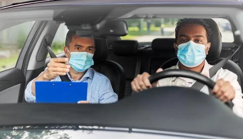 Car driving school instructor and driver in mask Stock Photos