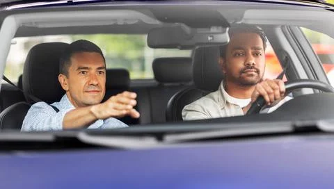 Car driving school instructor teaching male driver Stock Photos