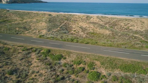 Car driving slow at beach road near turquoise calm sea waters and golden sand Stock Footage 135037445
