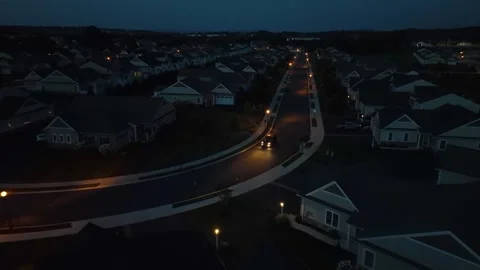 Car driving through dark American neighborhood at night. Aerial shot of Stock Footage 252115695