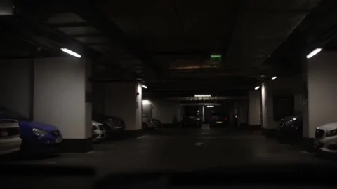The car is driving through a dark underground parking Stock Footage 153849070