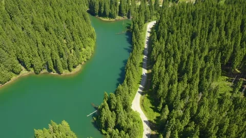 Car driving through the forest and the lake on the side. Beautiful mountain road Video stock 150588693