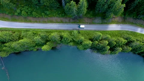 Car driving through the forest and the lake on the side. Beautiful mountain road 動画素材 150589395