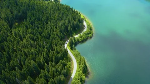 Car driving through the forest and the lake on the side. Beautiful mountain road Stock Footage 150589924