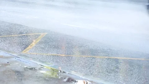 Car driving through a large puddle on a wet asphalt road, creating a splash.. Stock Footage 308364216