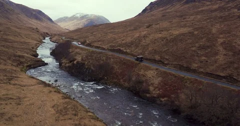 Car driving through mountainous landscape with large river drone aerial 4K Stock Footage 104584074