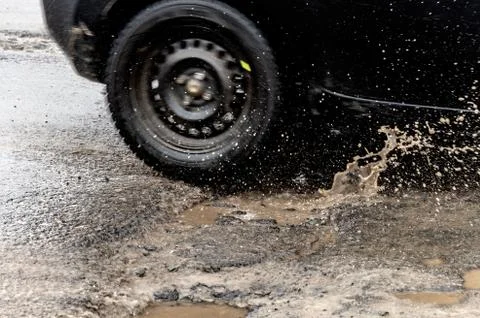 Car driving through a pothole with splashes of water Stock Photos