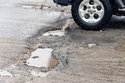 Car driving through a pothole with splashes of water Stock Photos