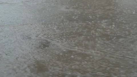 Car driving through a puddle and splashing water during a downpour Stock Footage 338409274