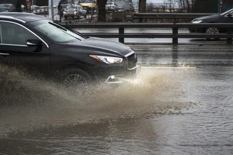 The car is driving through a puddle. Splashes from a puddle on the road. Stock Photos