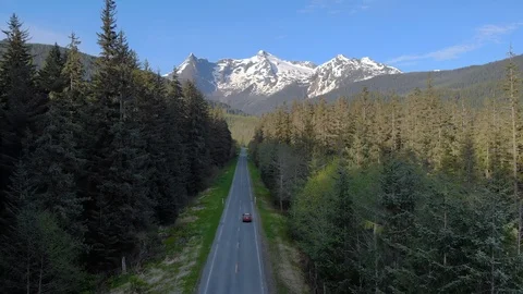Car driving through a road in the forest towards a mountain range Stock Footage 100640851