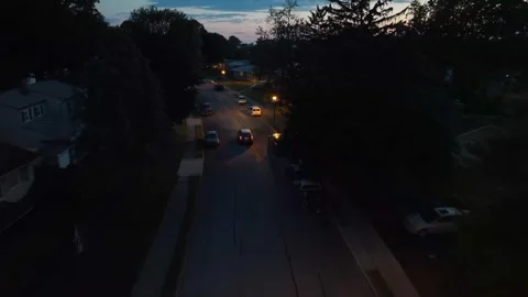 Car driving through small town community at night. Aerial tracking shot Stock Footage 248611048