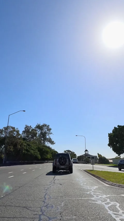 Car Driving Through Urban Intersection Under Bright Sunny Sky Stock Footage 341377207