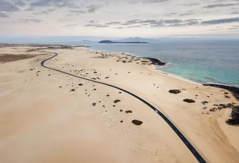 Car on the empty road, through the sand dunes, at Corralejo Natural Park befo Stock Photos