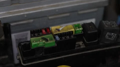 Car engine bay fuse box with melted green and yellow fuses. Stock Footage 344365017