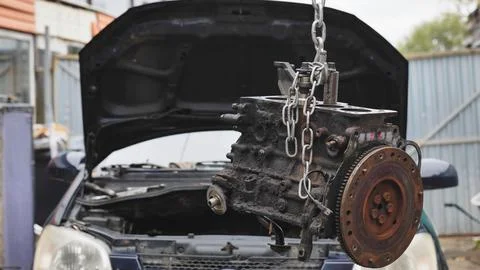 Car engine block hanging from chain for repair Foto stock