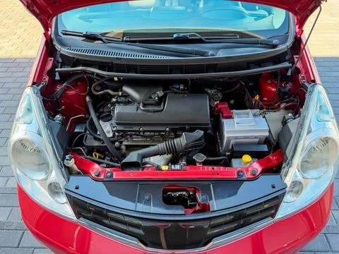 Car engine is open with components visible in a red vehicle parked in a gar.. Stock Photos