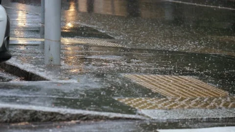 Car Entering a Puddle and Splashing on the Nearby Sidewalk during a Downpour Video stock 157356827