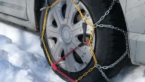 A car equipped with snow chains drives through snowy terrain. The close-up view Stock Footage 303574339