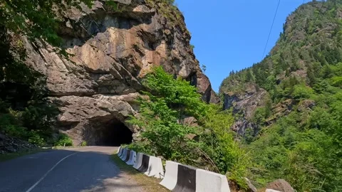 Car exits rock tunnel, forward view onto a mountain road in Svaneti Stock Footage 343774211