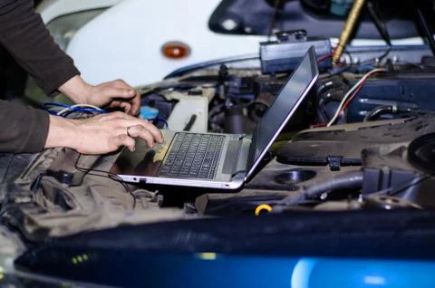 Car expert using laptop for auto diagnostics. Stock Photos
