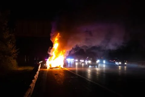 Car on fire night accident on the highway road Stock Photos