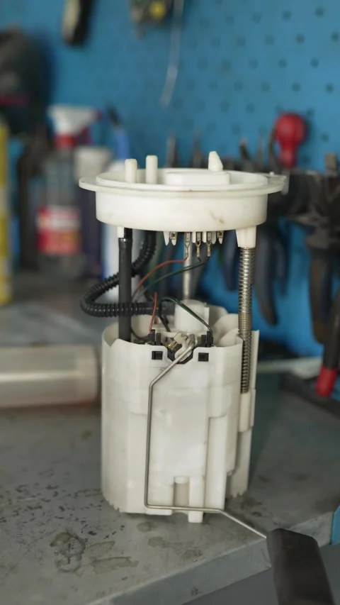 A car fuel pump module sits on a workshop workbench. Stock Footage 341331829