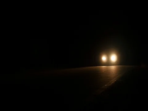 Car that goes by speed on a paved road all night illuminating the road with i Vídeos de archivo 80262742