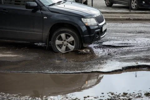 The car goes without reducing speed on a bad road with asphalt in pits and po Foto stock