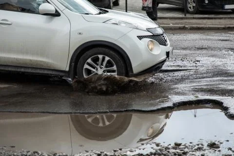 The car goes without reducing speed on a bad road with asphalt in pits and po Stock Photos