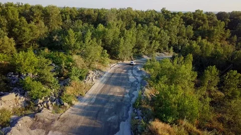 The car is going on a dirt road between trees and hills. 4k Stock Footage 94920713