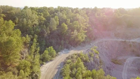 The car is going on a dirt road between trees and hills. 4k Stock Footage 94920989