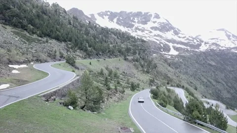 Car going down a road in the middle of the green mountains with some snow Video stock 221519914