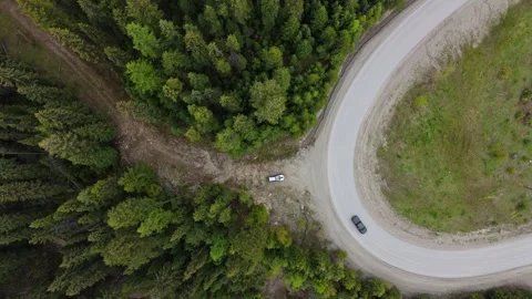 A car going down a winding road, surrounded by forest. Stock Footage 276988140