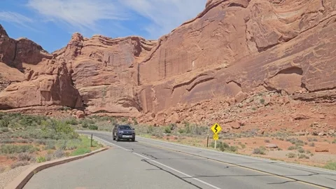 Car is going through Arches NP road. Red sandstone rocks. Utah, United States Stock Footage 304684195