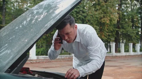 The car has broken down, the man consults by phone with the master Stock Footage 150121649