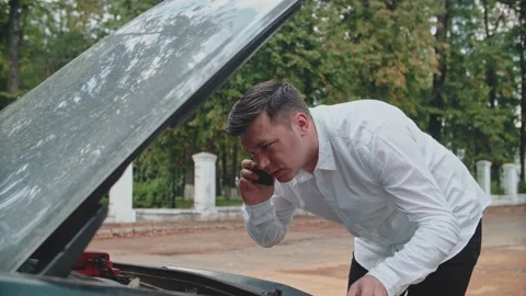 The car has broken down, a man is trying to fix the car malfunction Stock Footage 150121835