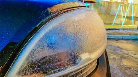 Car headlight is covered with ice and other hoarfrost. Stock Photos